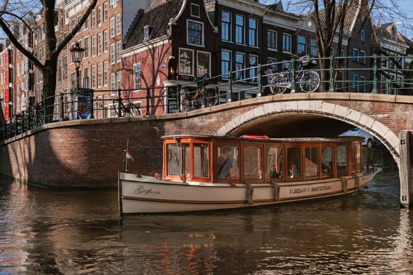 Un bateau de plaisance naviguant sur un canal, baptisé « Flagship Amsterdam », passe sous un pont où des vélos sont garés sur le dessus. 1