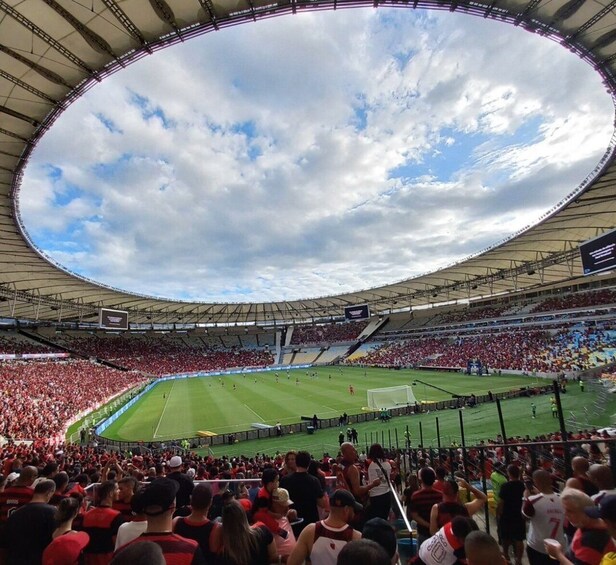 A stadium filled with spectators, a football field, and a partly cloudy sky. 5