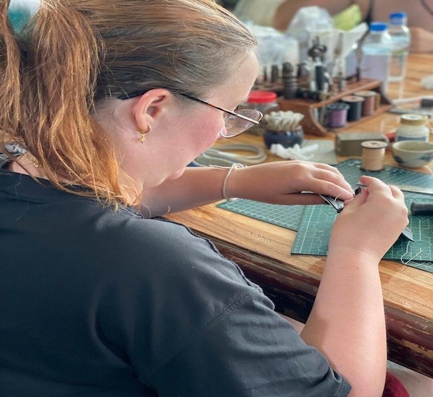 A person sewing at a table with various sewing tools and materials. 5