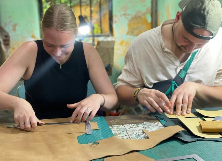 Two people working on a craft project with fabric and tools on a table. 2