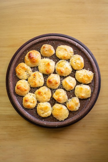 Un plat rond en céramique de couleur brun, contenant de petites pâtisseries de couleur brun doré disposées en cercle. 1