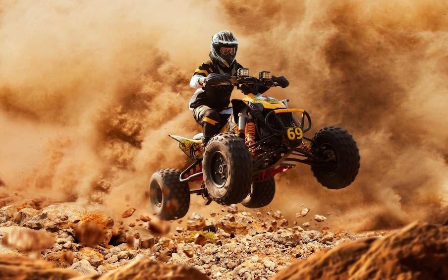 A person riding a quad bike on a rocky terrain. 3