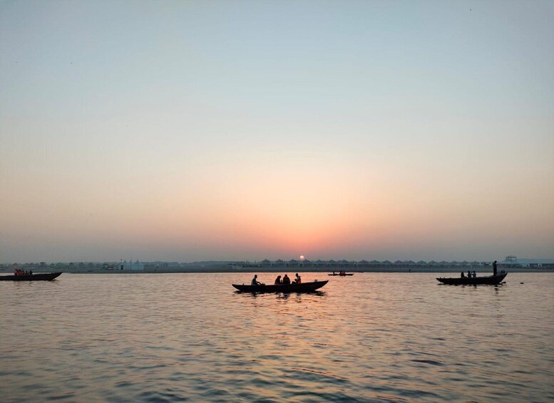 Un río tranquilo al atardecer con varias embarcaciones y gente en el agua. 1