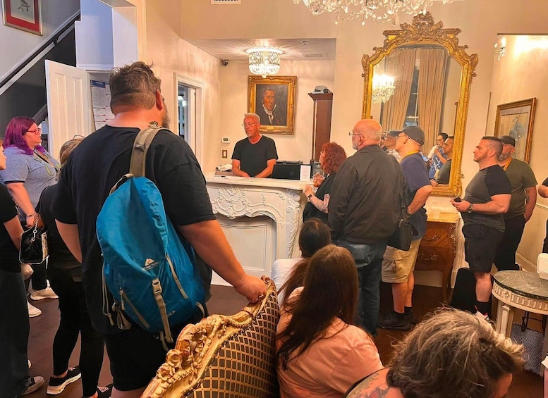 Un grupo de personas en una sala con un mostrador de recepción, una araña de cristal y un espejo grande. 5