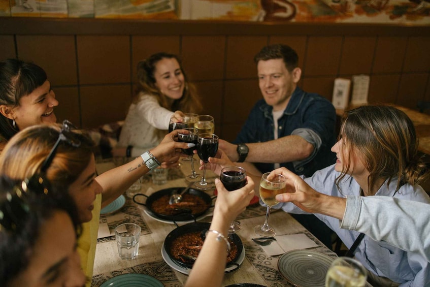 A group of people toasting with wine glasses at a dinner table with dishes. 1