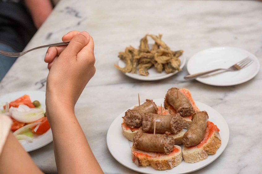 A plate of meat rolls on toast with a side of fried fish. 2