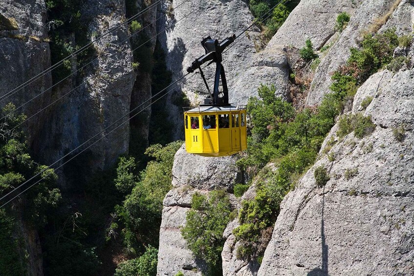 A yellow cable car suspended between rocky cliffs. 2