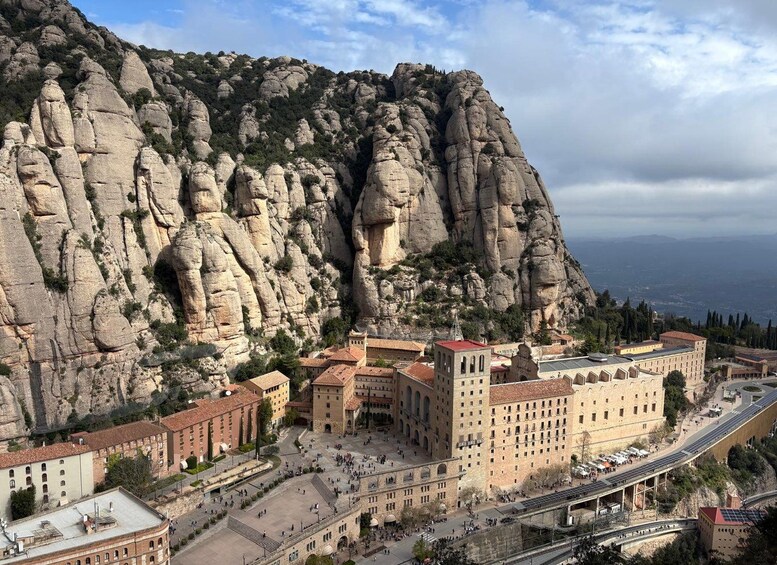A historic building complex with a large rock formation in the background. 4