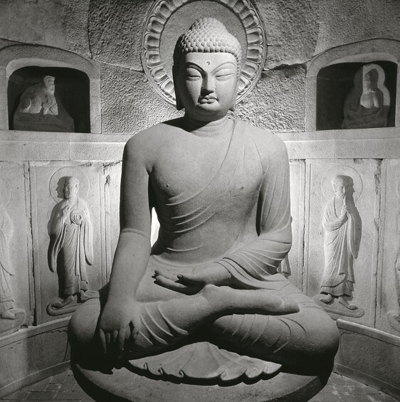 Una gran estatua de Buda sentado en un templo, con estatuas más pequeñas en hornacinas. 5