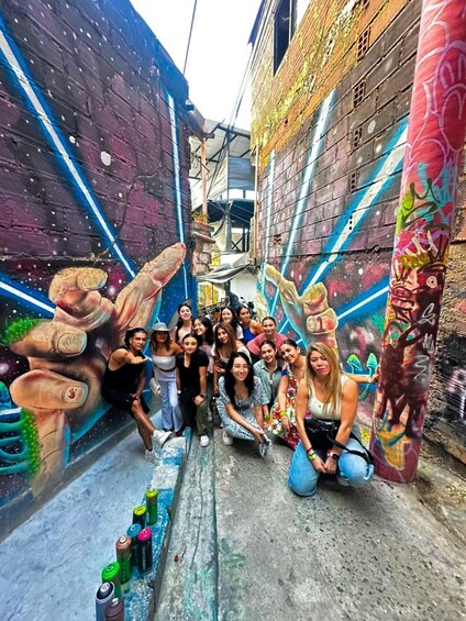 A group of people posing in front of a colorful mural in an alleyway. 2