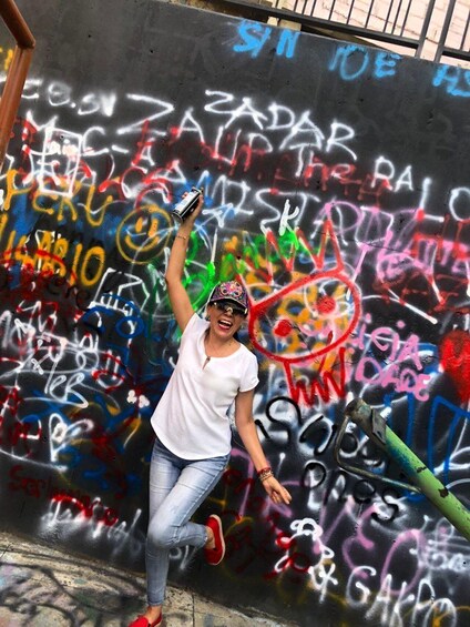 A person jumping in front of a graffiti-covered wall. 1