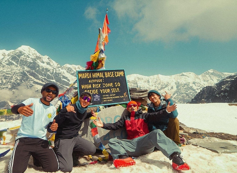 A group of people at a high-altitude base camp with a sign indicating it's a high-risk zone. 1