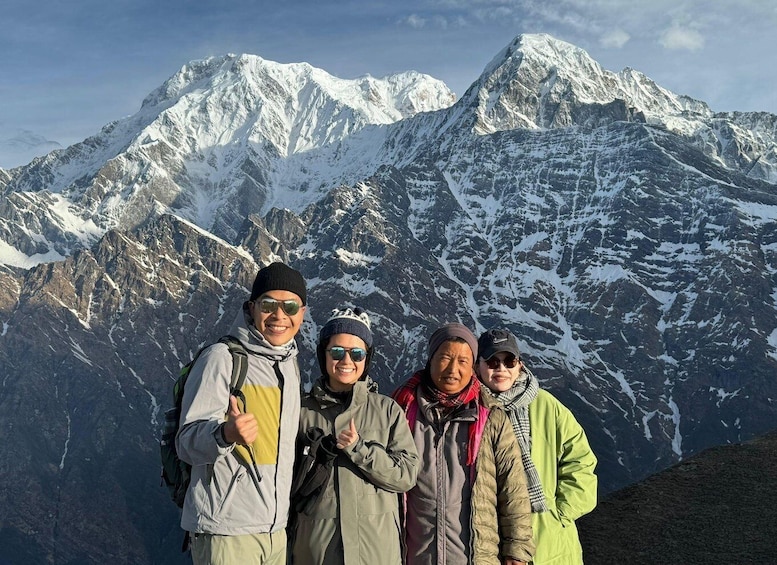 A group of people standing on a mountain ridge with snow-covered peaks in the background. 5