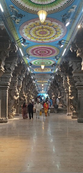 A temple corridor with ornate ceiling artwork and stone carvings. 2