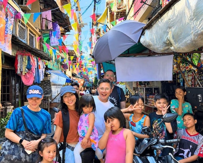 A group of people in a narrow street with colorful flags and various shops. 1