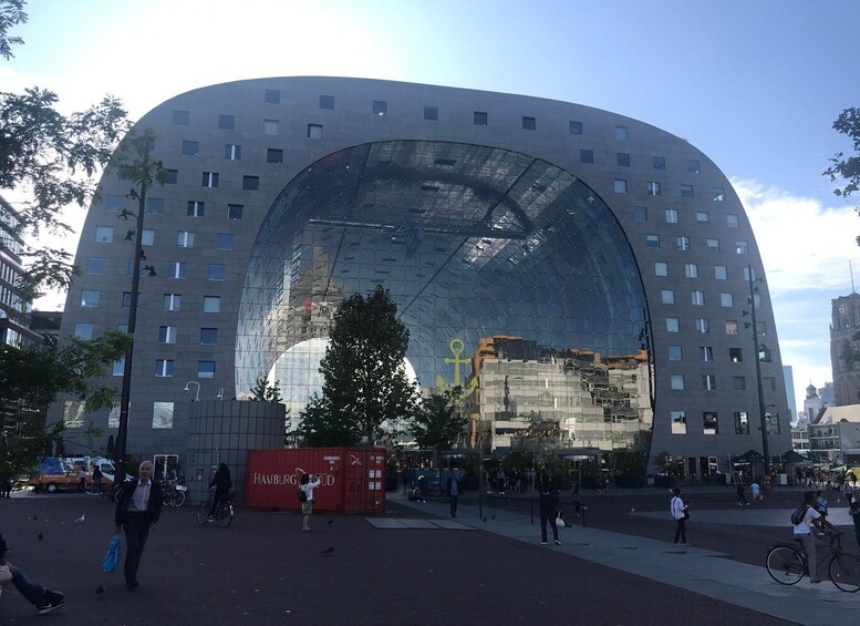 A modern curved building with a glass facade, surrounded by a public square with people and bicycles. 5