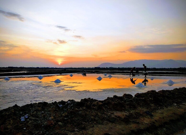 A sunset over a salt flat with people working. 1