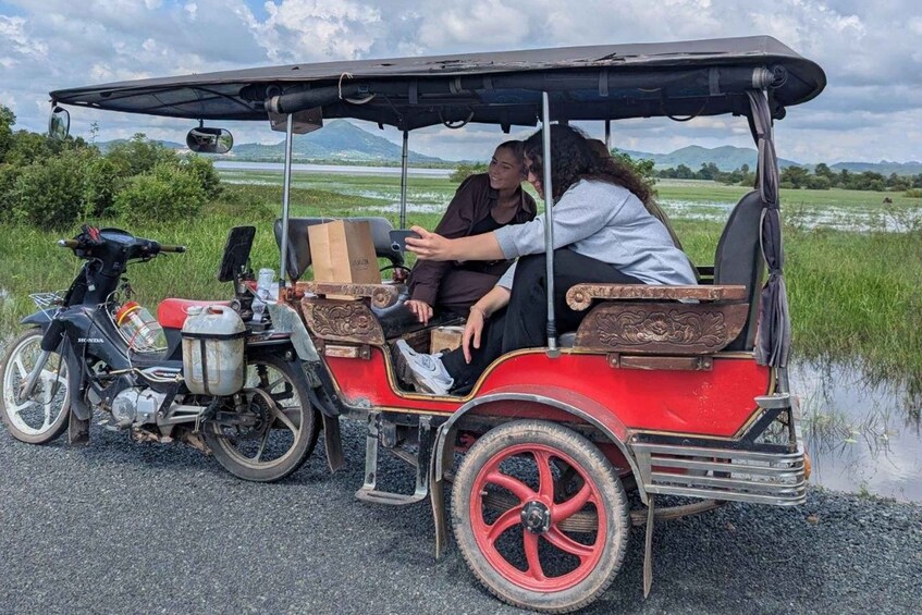 A red carriage with passengers, a motorcycle, and a water body in the background. 1