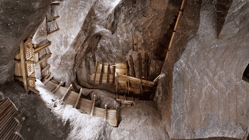 Una escalera de piedra en una cueva con barandillas y peldaños de madera. 4