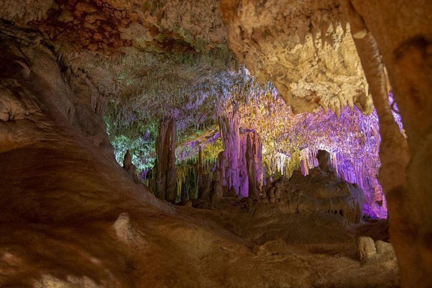 A cave with stalactites and stalagmites, illuminated by artificial lighting. 4