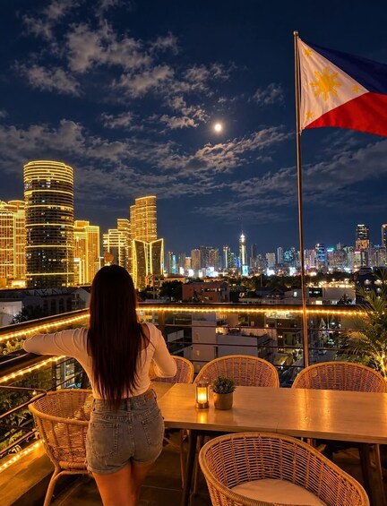 A cityscape at night with illuminated buildings, a flag, and a person overlooking the view. 1