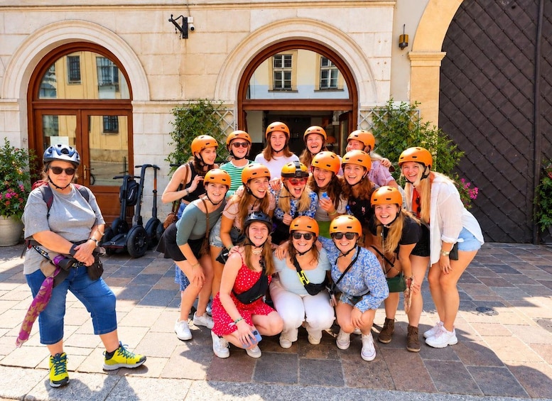 A group of people wearing helmets, posing in front of a building with arched windows and a door. 4
