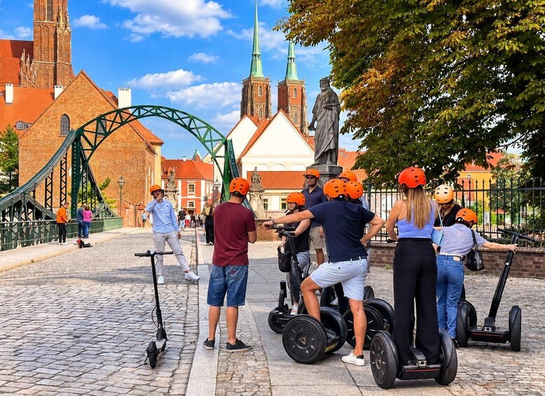 People riding Segways on a cobblestone street with a green bridge and a church in the background. 2