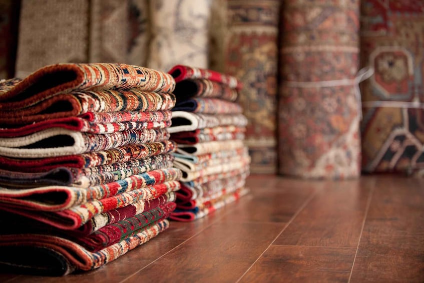 A stack of colorful woven rugs on a wooden floor. 2
