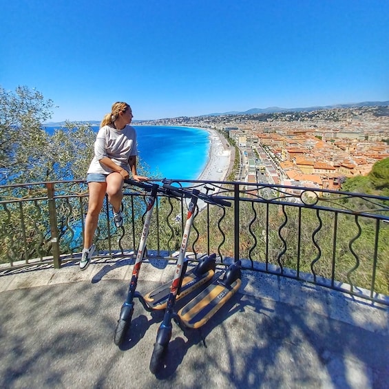 A person sitting on a railing overlooking a coastal city with a clear blue sea and a view of the cityscape. 2