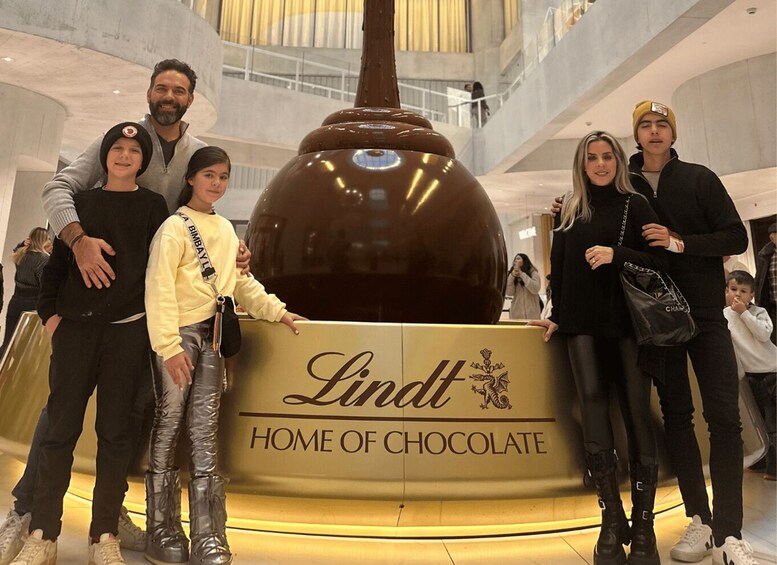 A family posing in front of a Lindt chocolate display in a mall. 1
