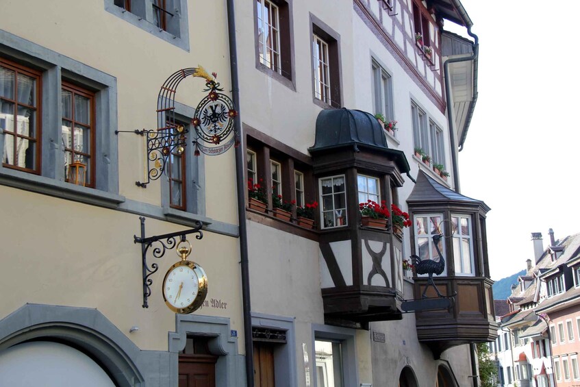 A street with traditional European architecture, including a building with a clock and a street lamp with flowers. 4