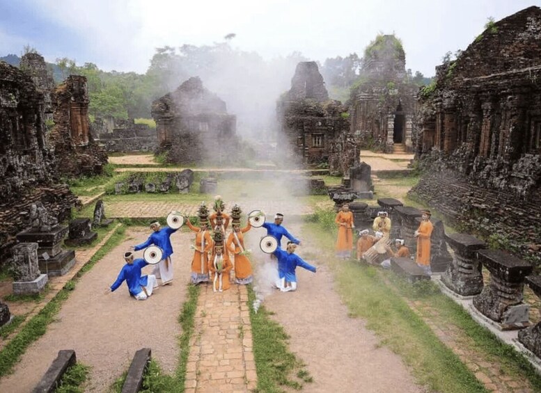 A temple complex with stone ruins and a group of people in traditional attire performing a ritual. 3