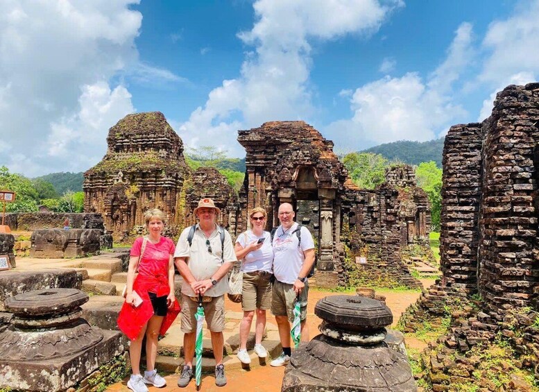 A group of tourists standing in front of ancient stone ruins with a mountainous landscape in the background. 4