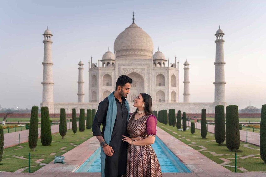 A couple standing in front of the Taj Mahal with a symmetrical garden pathway. 4