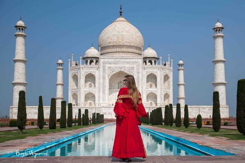 The Taj Mahal with a person in a red dress standing in front. 5