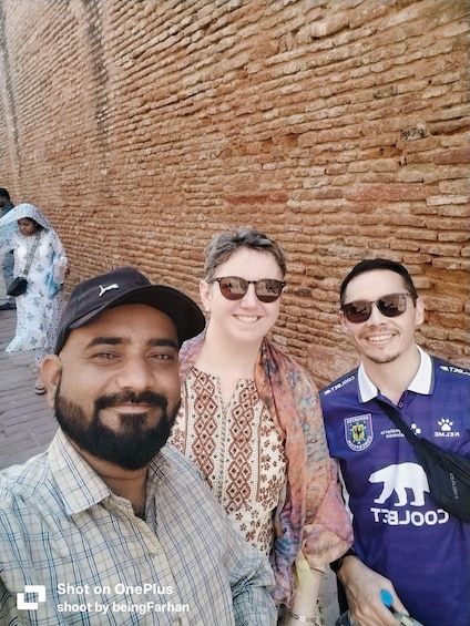 Three people standing in front of a brick wall. 5