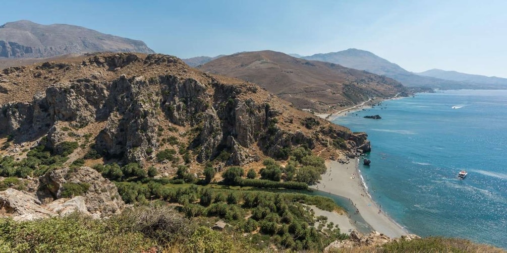 A coastal landscape with rocky cliffs, a beach, and a clear blue sea. 3