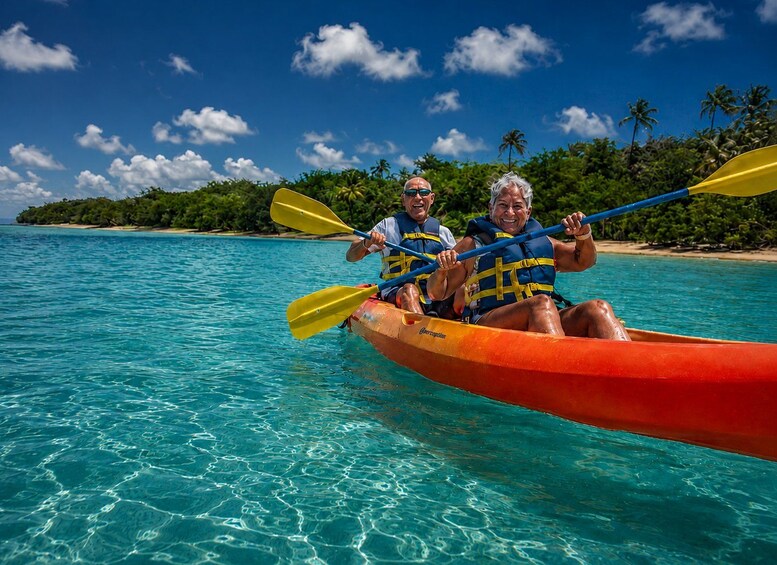 Two people kayaking on turquoise water with a tropical island in the background. 4