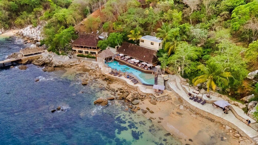 A resort with a pool, beach, and rocky coastline. 2