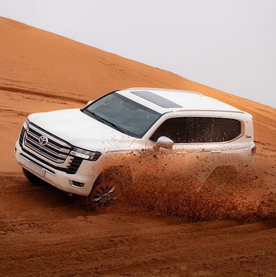 A white SUV driving through a sandy desert landscape. 1