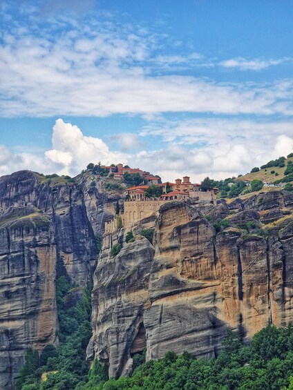 A mountainous landscape with a historic building perched on a cliff. 1