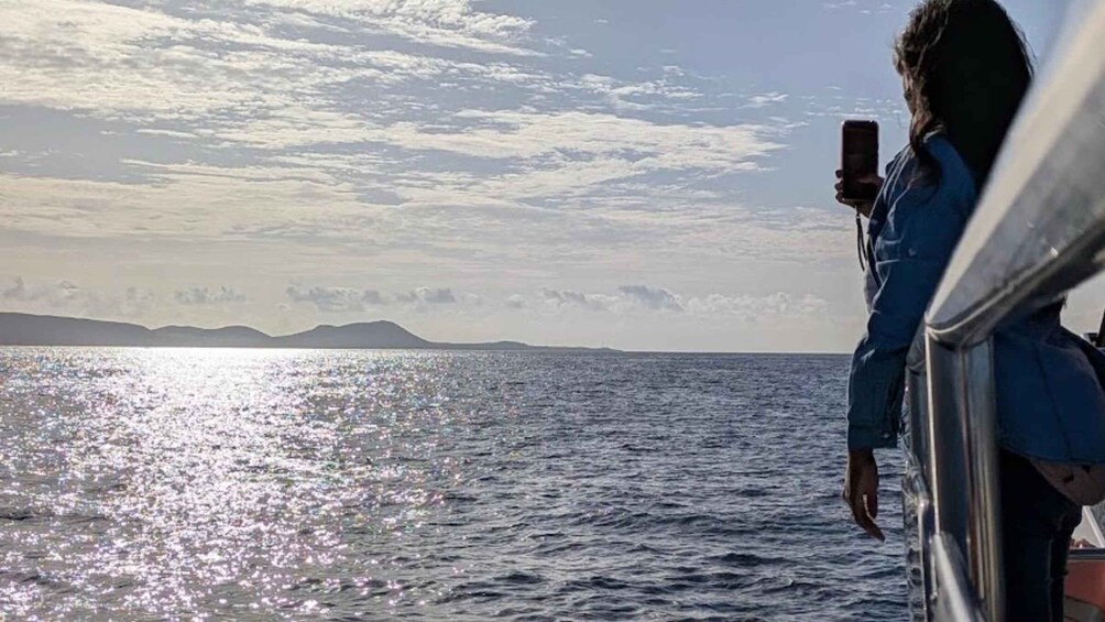 A person taking a photo of a body of water with a distant landmass under a cloudy sky. 3