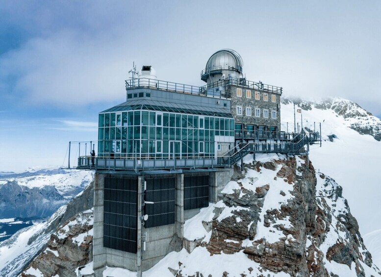 A glass observatory on a snowy mountain peak with a dome structure. 1