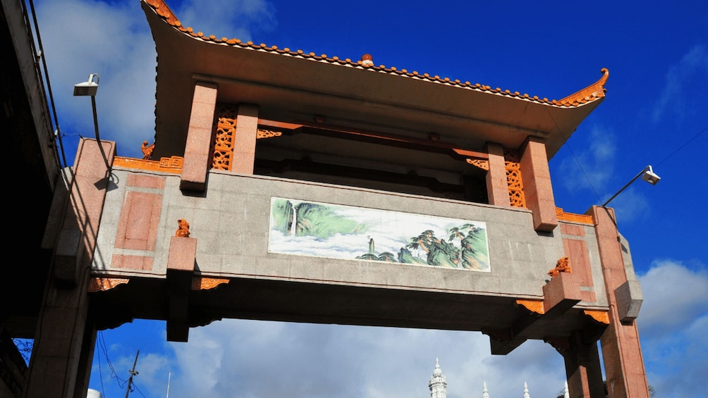 A traditional Chinese gate with a tiled roof and a mural of a landscape. 3