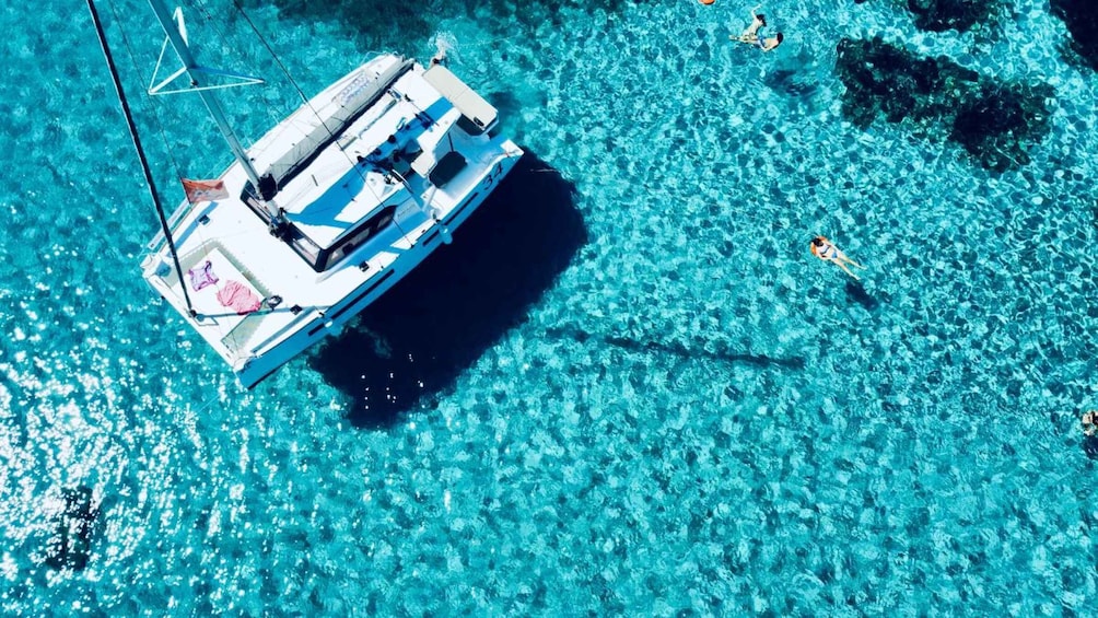 Een witte jacht met het nummer 34, afgemeerd in helder turquoise water. 1