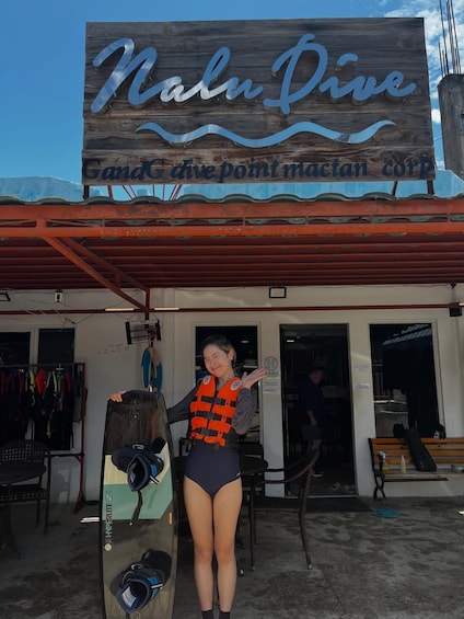A woman in a life jacket standing in front of a diving shop named 'Nalu Dive.' 5
