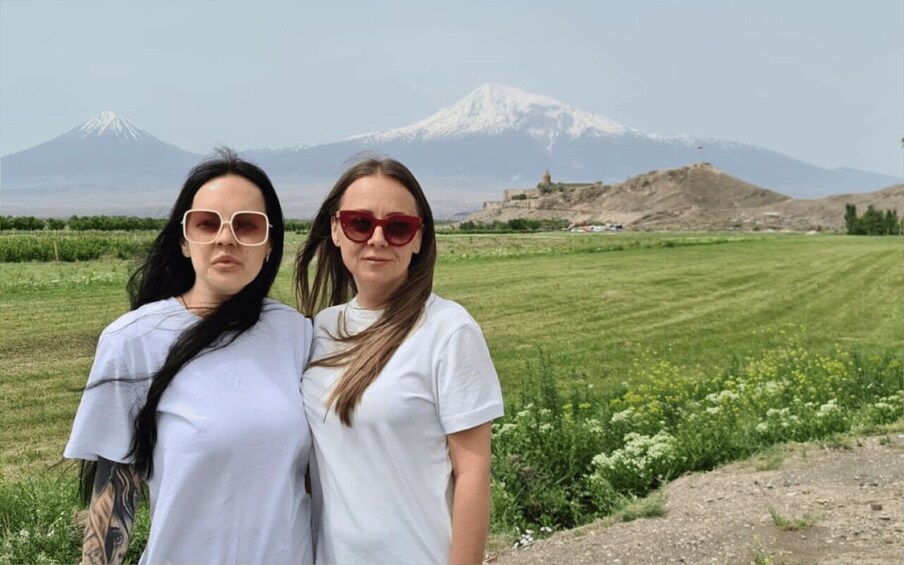 Dos personas de pie en un campo, con una montaña al fondo. 4