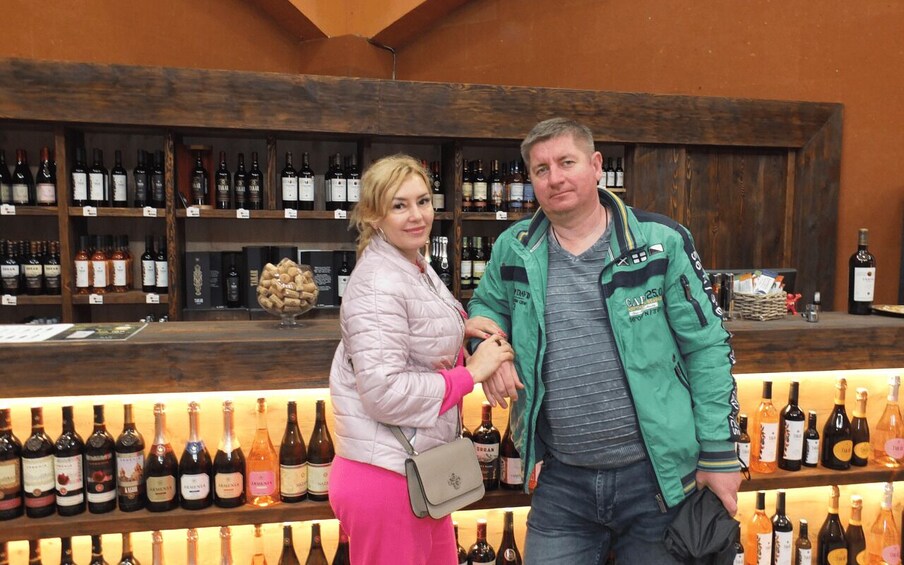 Dos personas frente a una vitrina con varias botellas de vino. 2