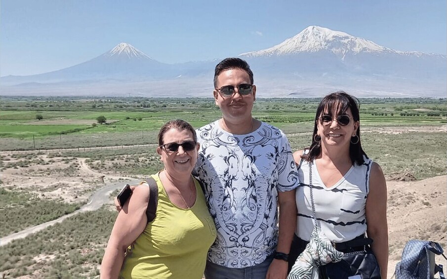 Tres personas de pie con una montaña al fondo. 5