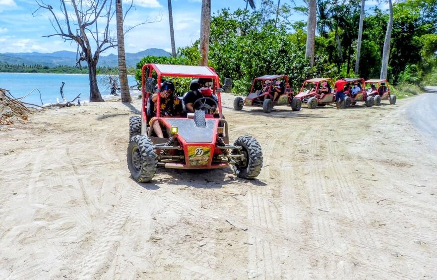 Off-road vehicles on a sandy path with a lake and trees in the background. 3